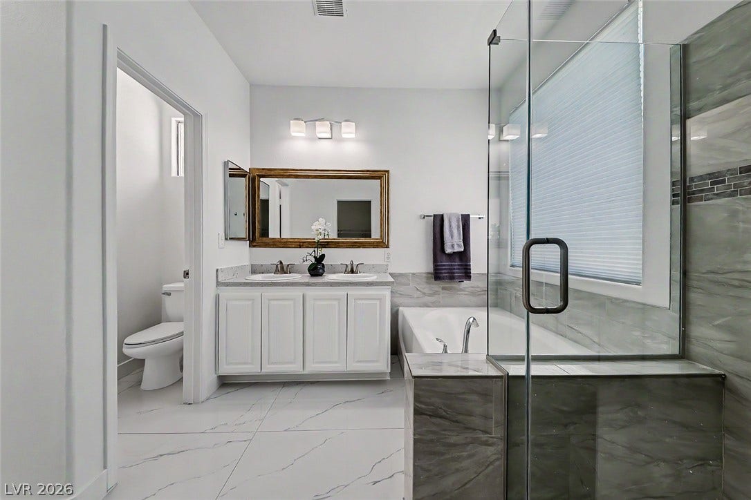 792 Valley Rise Drive, Henderson, NV 89052 Marble-style tiling flows across the floor of this updated bathroom featuring a glass-enclosed shower.