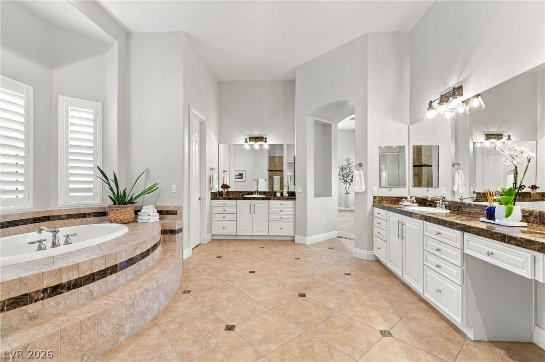 210 Torrey Morgan Way, Henderson, NV 89074 An elevated soaking tub and generous vanities anchor this spacious tiled bathroom retreat.