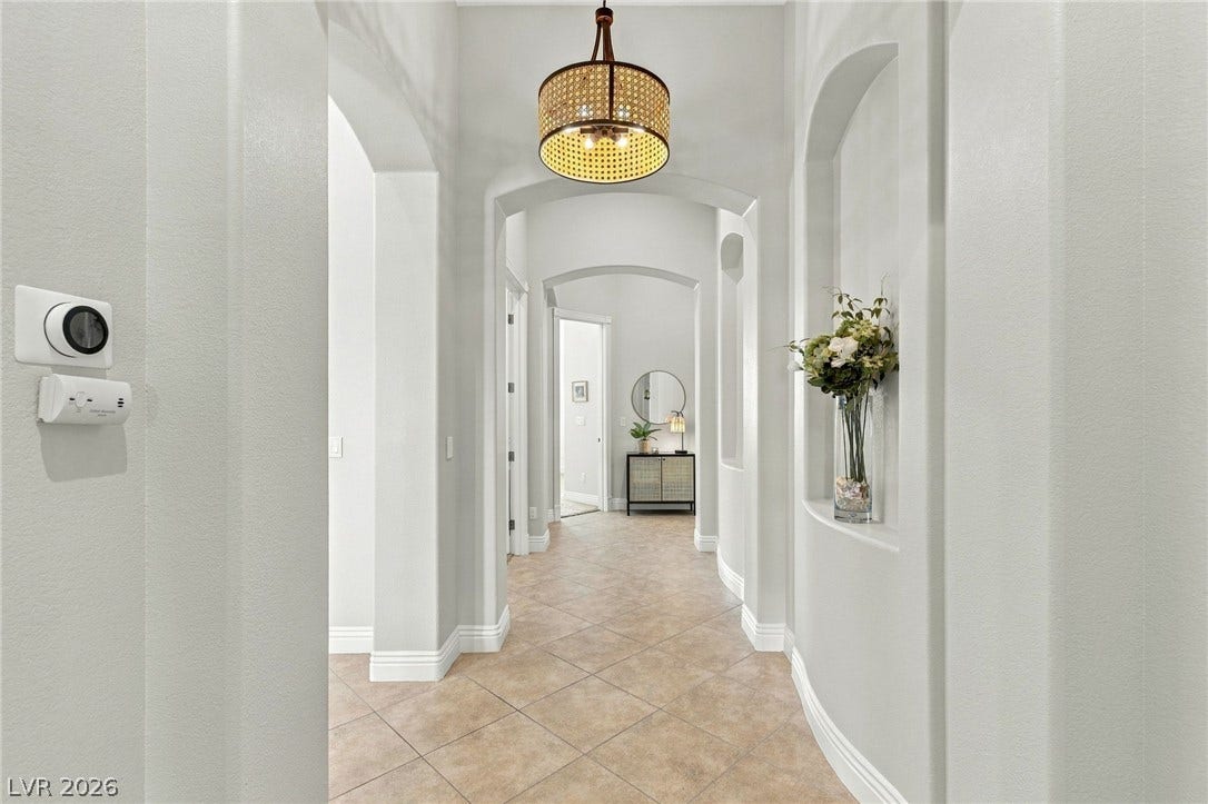 210 Torrey Morgan Way, Henderson, NV 89074 Elegant arched transitions and neutral tile flooring guide the way through this inviting hallway.