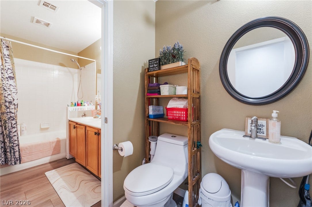 5348 Reardon Court, North Las Vegas, NV 89031 Functional design highlights this multi-area bathroom layout featuring a classic pedestal sink and wood-look flooring.