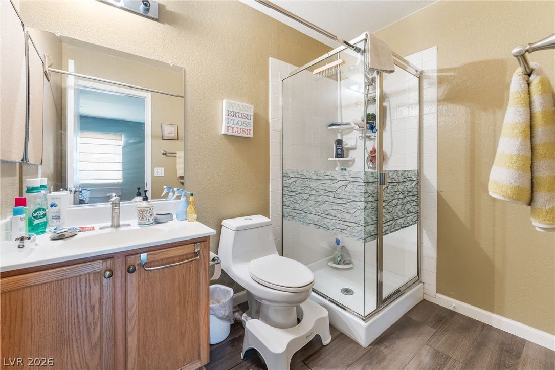 5348 Reardon Court, North Las Vegas, NV 89031 Functional layout features a wood vanity, laminate flooring, and a corner glass shower enclosure.