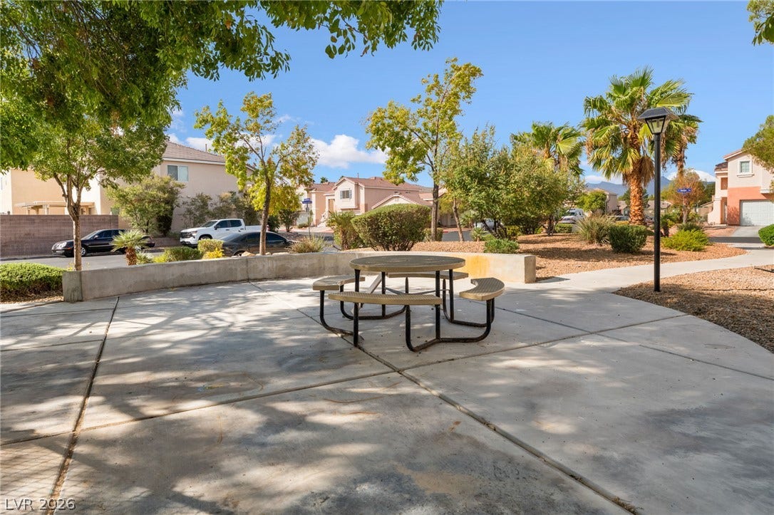 5348 Reardon Court, North Las Vegas, NV 89031 A shaded concrete patio area sits surrounded by manicured landscaping and mature trees.