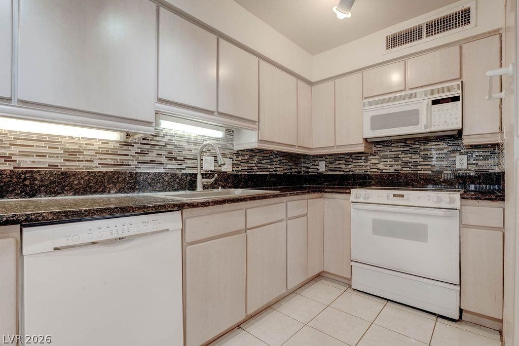 3111 Bel Air Drive, #3A, Las Vegas, NV 89109 Ample cabinetry pairs with stone countertops and a mosaic tile backsplash in this efficient kitchen.