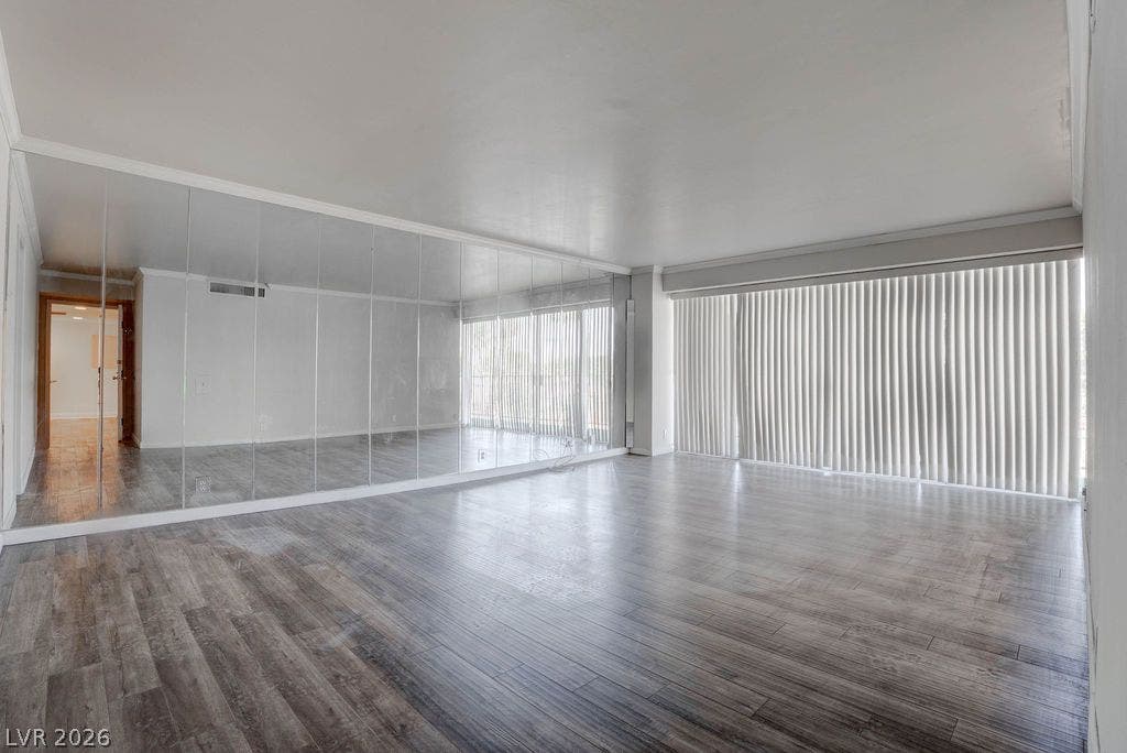 3111 Bel Air Drive, #3A, Las Vegas, NV 89109 Plank flooring and a full-length mirrored accent wall define this versatile interior space.