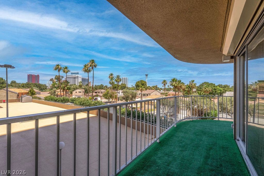 3111 Bel Air Drive, #3A, Las Vegas, NV 89109 A curved private balcony overlooks palm trees and the distant city skyline.