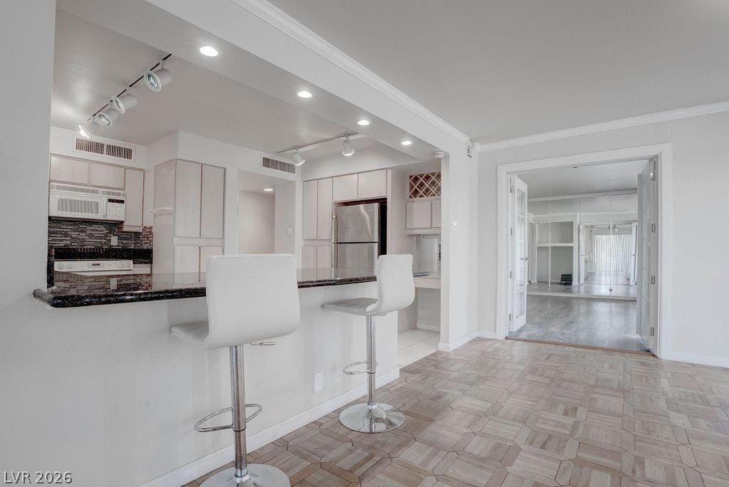 3111 Bel Air Drive, #3A, Las Vegas, NV 89109 Polished stone counters and intricate parquet wood flooring define this open breakfast bar setup.