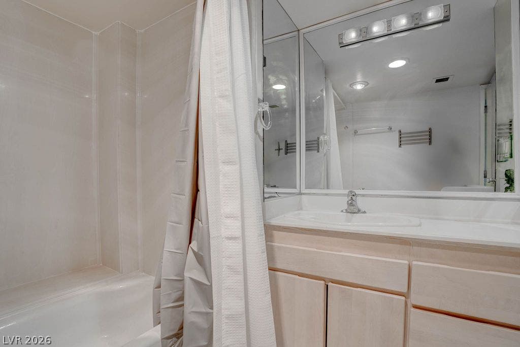 3111 Bel Air Drive, #3A, Las Vegas, NV 89109 Functional layout pairs a classic bathtub with a light wood vanity and large mirror.