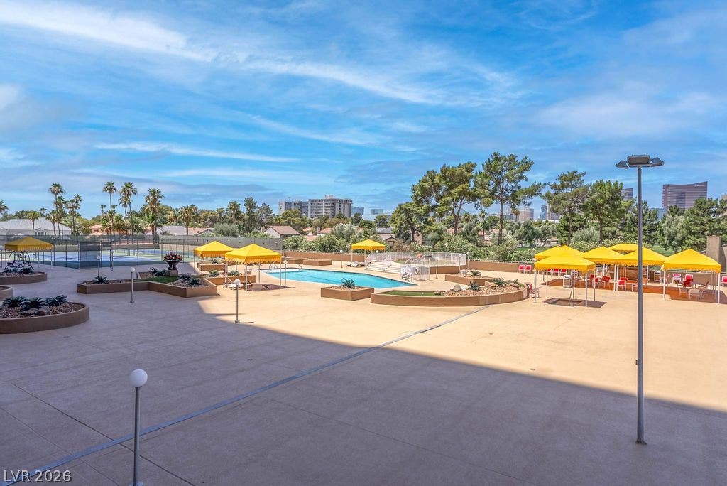 3111 Bel Air Drive, #3A, Las Vegas, NV 89109 An expansive concrete recreation deck hosts a sparkling swimming pool and tennis courts under open skies.