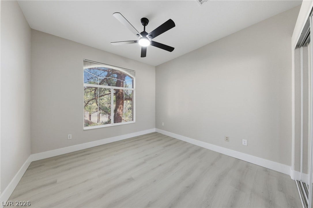 104 Lemon Glaze Street, #204, Las Vegas, NV 89145 An arched window frames outdoor views in this bedroom featuring modern plank flooring.
