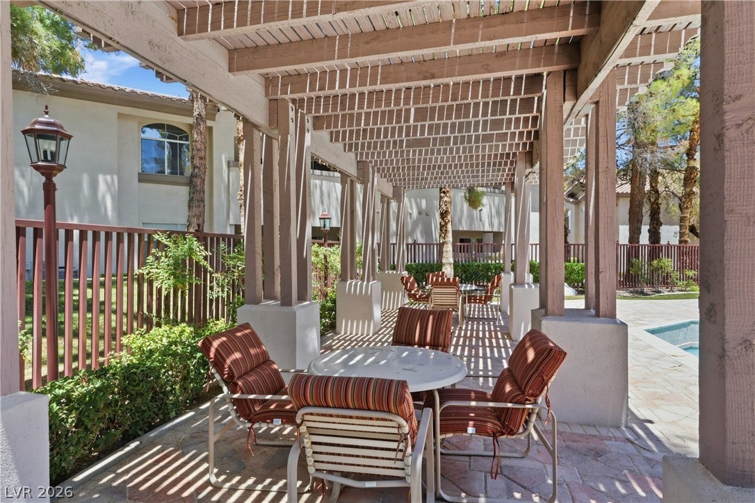 104 Lemon Glaze Street, #204, Las Vegas, NV 89145 A shaded patio under a classic wooden pergola sits adjacent to the pool area.