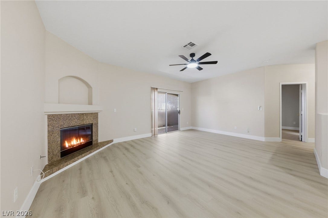 104 Lemon Glaze Street, #204, Las Vegas, NV 89145 An inviting fireplace and sliding glass doors highlight this open living space with wood-look flooring.