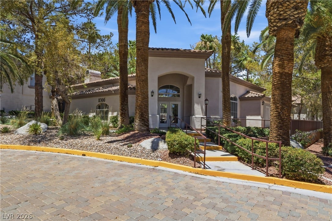 104 Lemon Glaze Street, #204, Las Vegas, NV 89145 Soaring palm trees frame a paved driveway leading to the welcoming double-door entry.