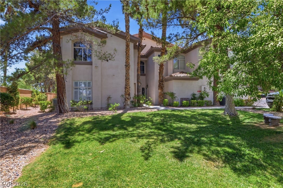 104 Lemon Glaze Street, #204, Las Vegas, NV 89145 Mature trees frame the stucco exterior of this multi-level home with a grassy lawn.