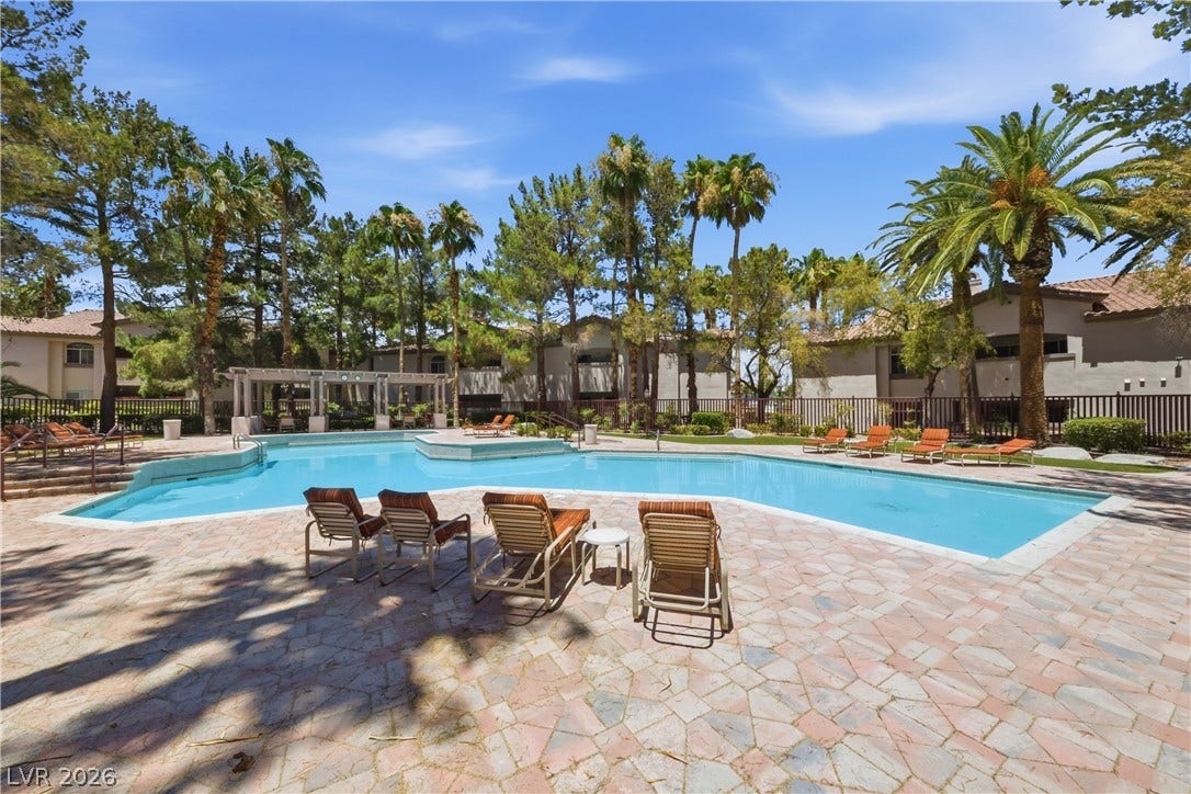 104 Lemon Glaze Street, #204, Las Vegas, NV 89145 Lush palm trees and stone pavers surround a crystal blue community swimming pool.