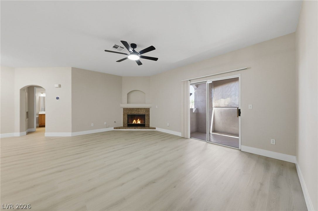 104 Lemon Glaze Street, #204, Las Vegas, NV 89145 A corner fireplace and glass sliding doors highlight this open living space with light wood-style flooring.