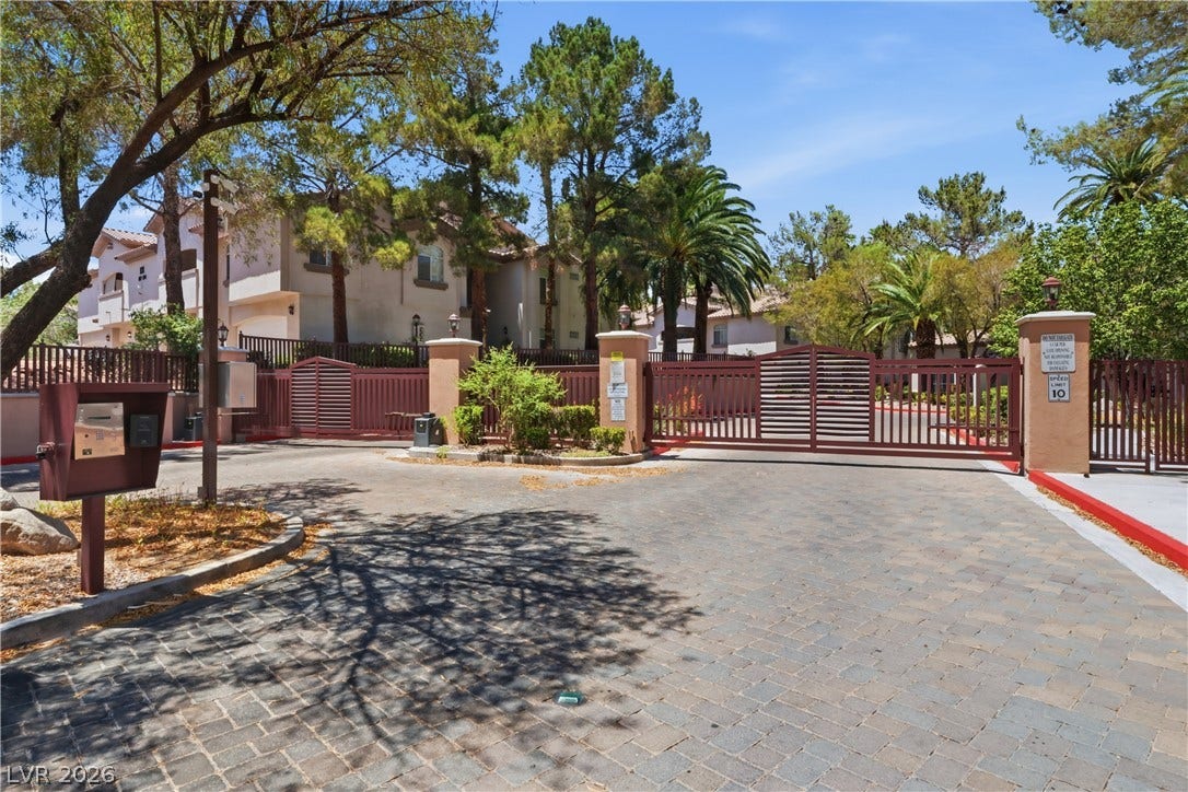 104 Lemon Glaze Street, #204, Las Vegas, NV 89145 Mature trees shade the paver entry driveway leading to a secure, gated community entrance.