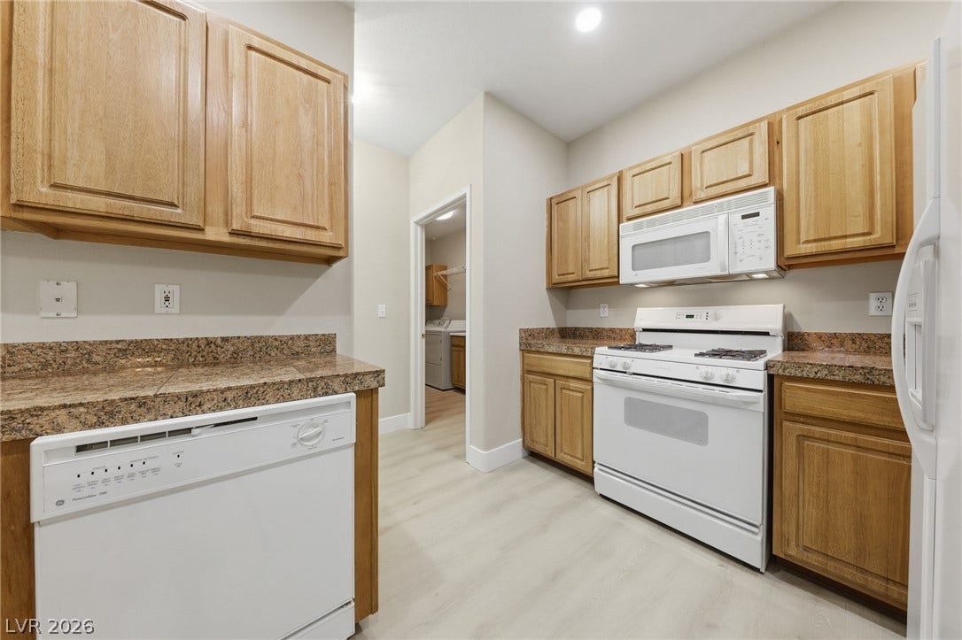 104 Lemon Glaze Street, #204, Las Vegas, NV 89145 Ample wooden cabinetry and stone tile countertops flank a functional kitchen workspace.