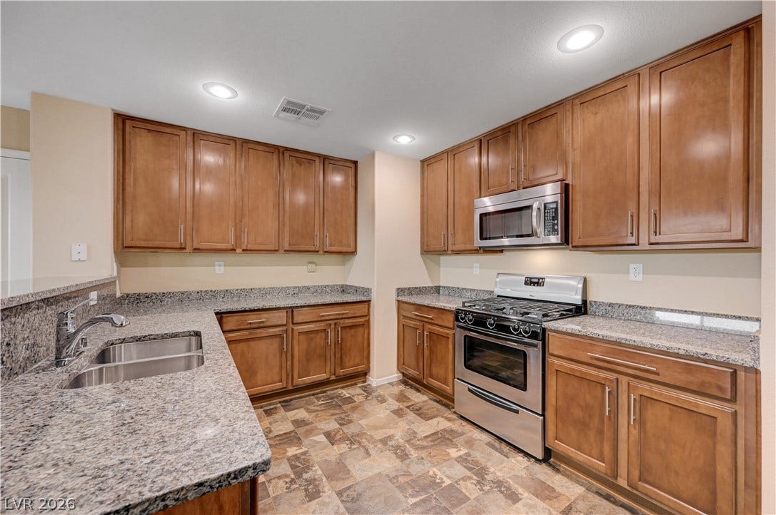 2088 Artistic Flair Walk, Henderson, NV 89044 Rich wood cabinetry pairs beautifully with expansive granite countertops in this functional kitchen layout.