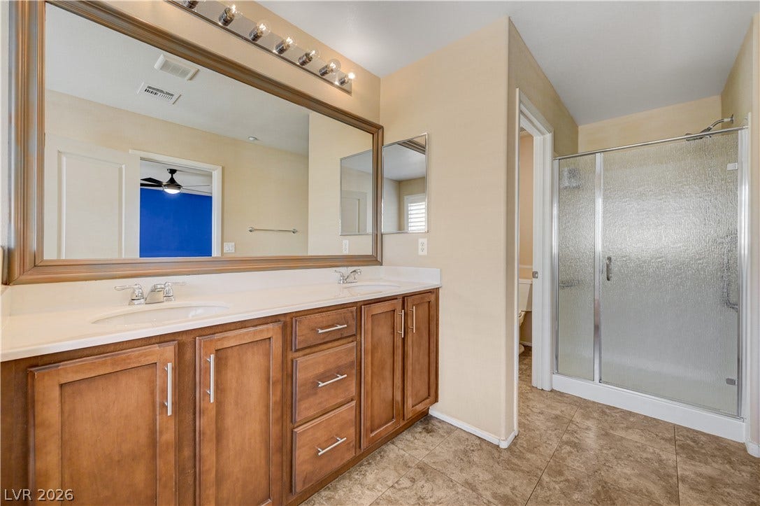 2088 Artistic Flair Walk, Henderson, NV 89044 A spacious vanity with dual sinks anchors this bathroom complete with a glass-enclosed shower.