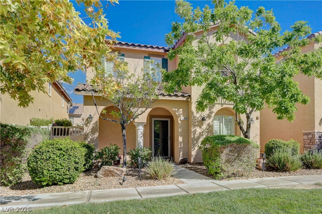 2088 Artistic Flair Walk, Henderson, NV 89044 Mature trees shade the inviting arched entryway of this two-story stucco home.