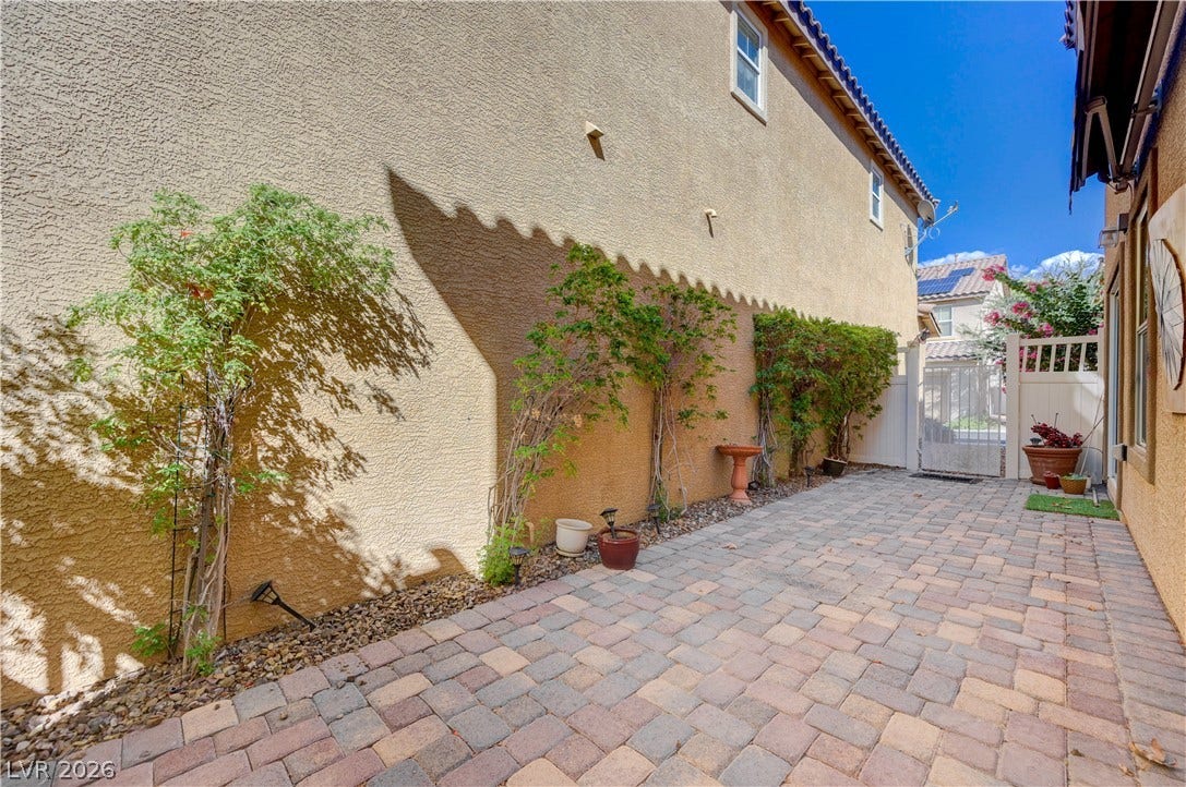 2088 Artistic Flair Walk, Henderson, NV 89044 A private stone paver courtyard features stucco exterior walls and established climbing greenery.