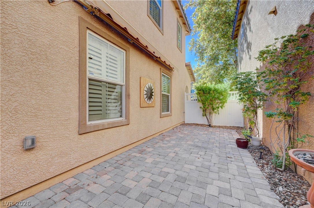 2088 Artistic Flair Walk, Henderson, NV 89044 An inviting paved patio pathway leads alongside the classic stucco exterior of the home.