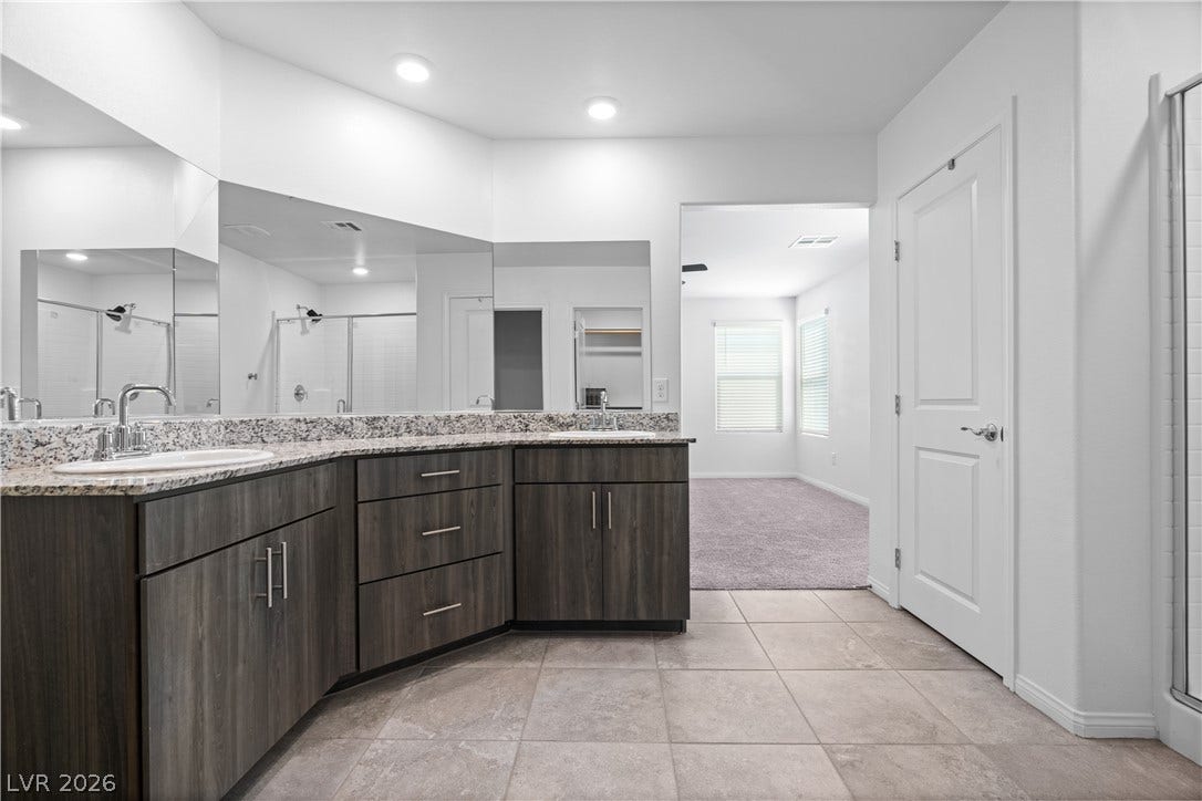 4429 Ginger Hills Avenue, Las Vegas, NV 89141 Granite counters and dual vanities anchor this spacious primary bath with tile flooring.