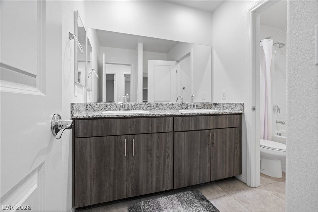 4429 Ginger Hills Avenue, Las Vegas, NV 89141 A contemporary vanity with stone countertops highlights this sleek, modern bathroom space.