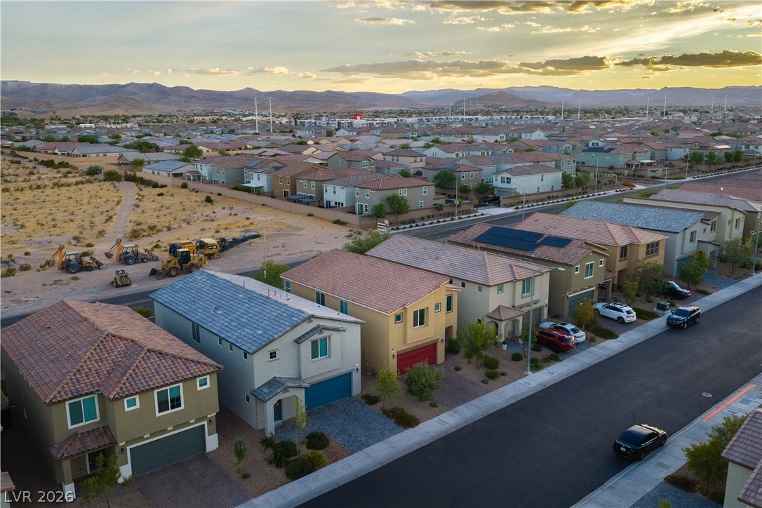 4429 Ginger Hills Avenue, Las Vegas, NV 89141 Distant mountains frame a quiet neighborhood of multi-level homes along a paved suburban street.
