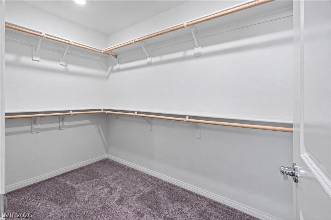 4429 Ginger Hills Avenue, Las Vegas, NV 89141 Ample built-in shelving and hanging rods maximize storage space within this carpeted walk-in closet.