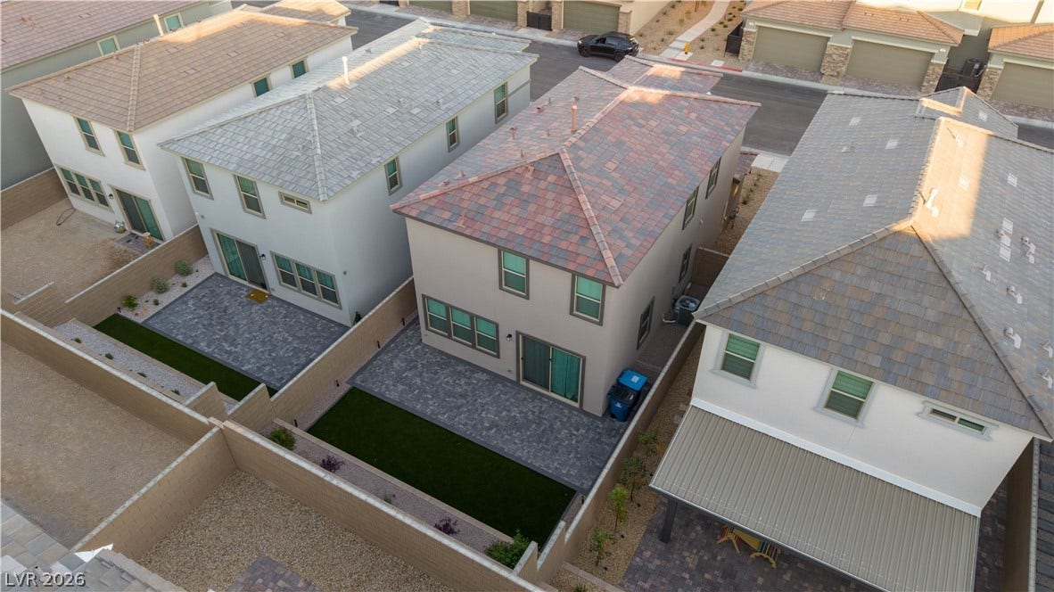 Aerial perspective highlights a neatly paved patio and low-maintenance yard within a modern residential community.