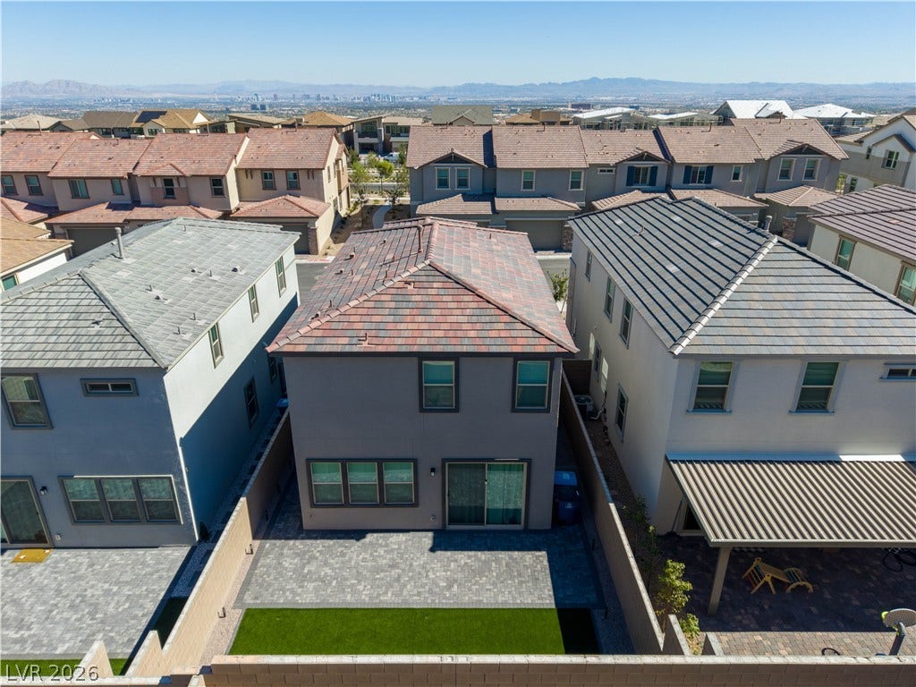 An aerial perspective showcases the tiled roofline and paved rear patio in a modern neighborhood.