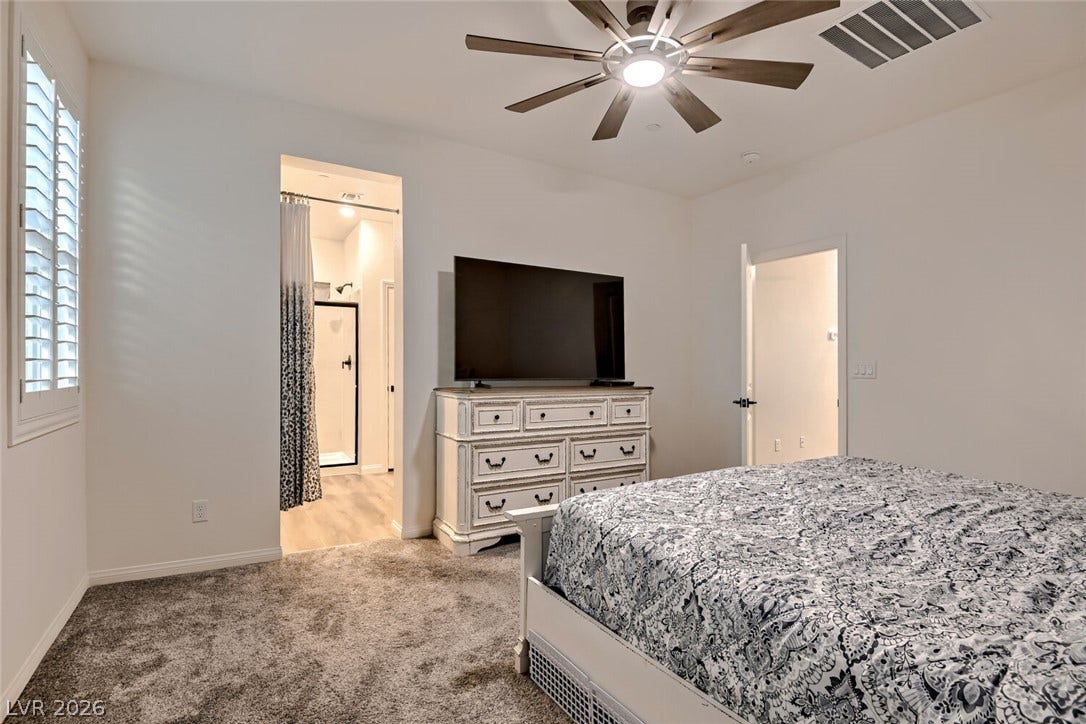 Plush carpeting and plantation shutters highlight this comfortable main-level bedroom suite.
