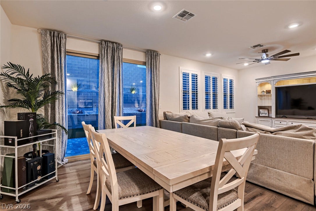 An open living and dining layout showcases wide sliding glass doors and rich wood-style flooring.