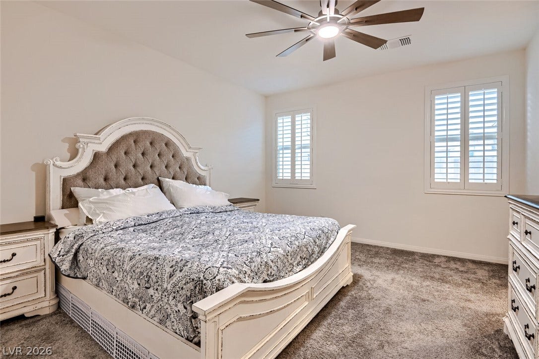 Plush wall-to-wall carpeting and plantation shutters define this inviting bedroom space.