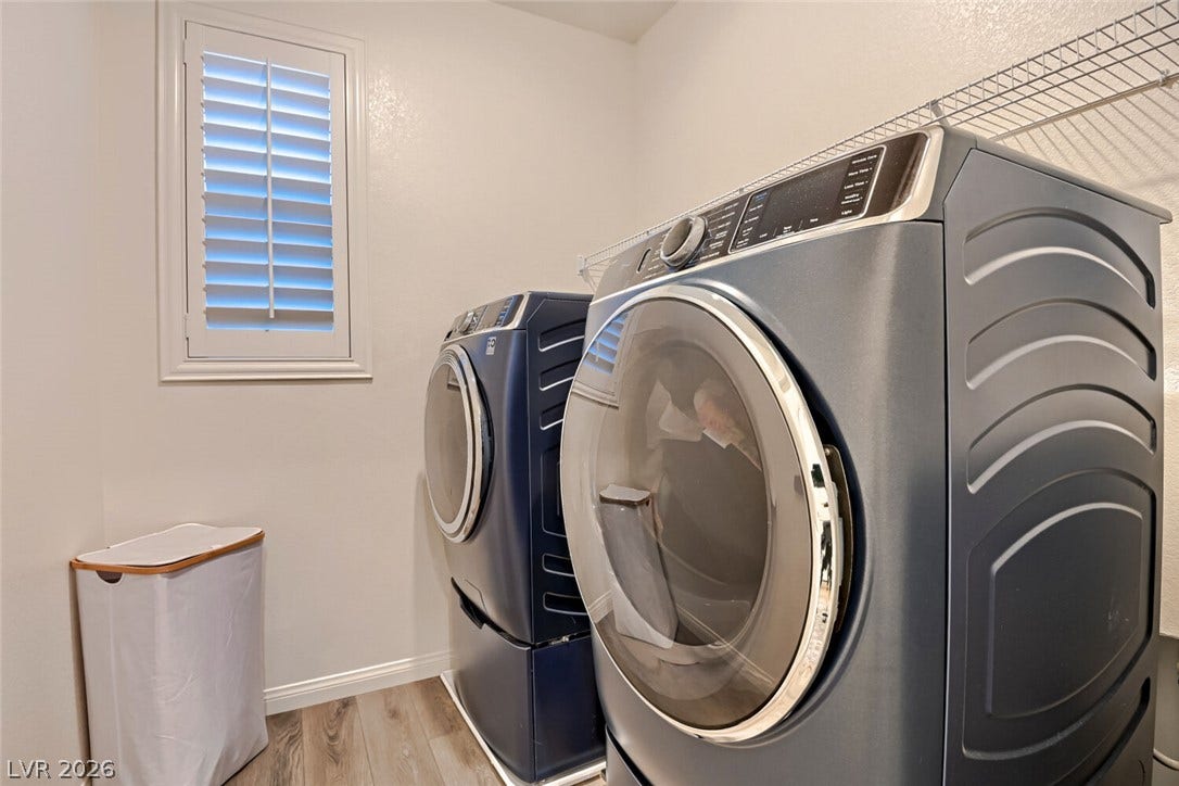 An organized laundry room features modern appliances and a bright window with shutters.