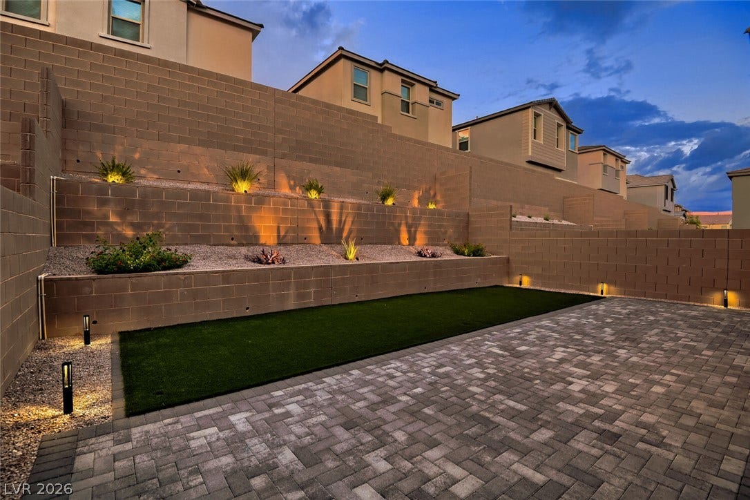 Multi-level retaining walls and integrated lighting frame this paved patio and low-maintenance yard.