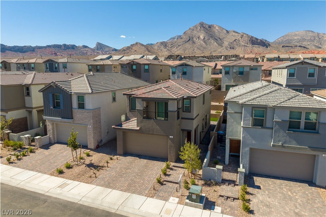 Dramatic mountain vistas rise behind a row of modern multi-level suburban residences.