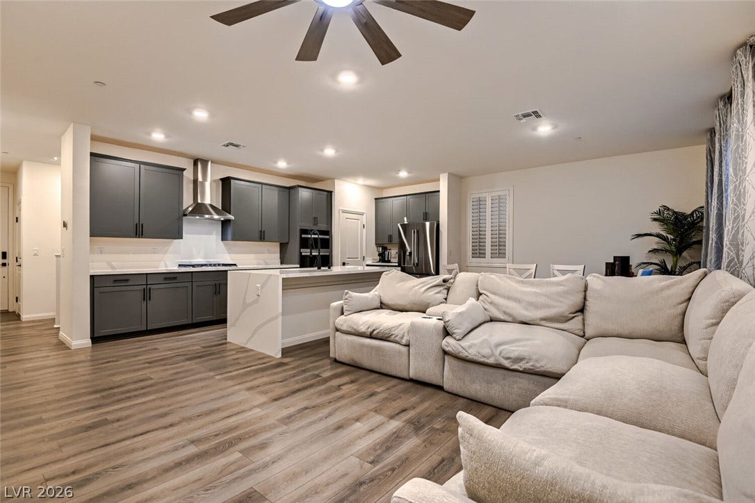 Smooth wood-look flooring stretches across a modern open-concept layout connecting the living area and kitchen.