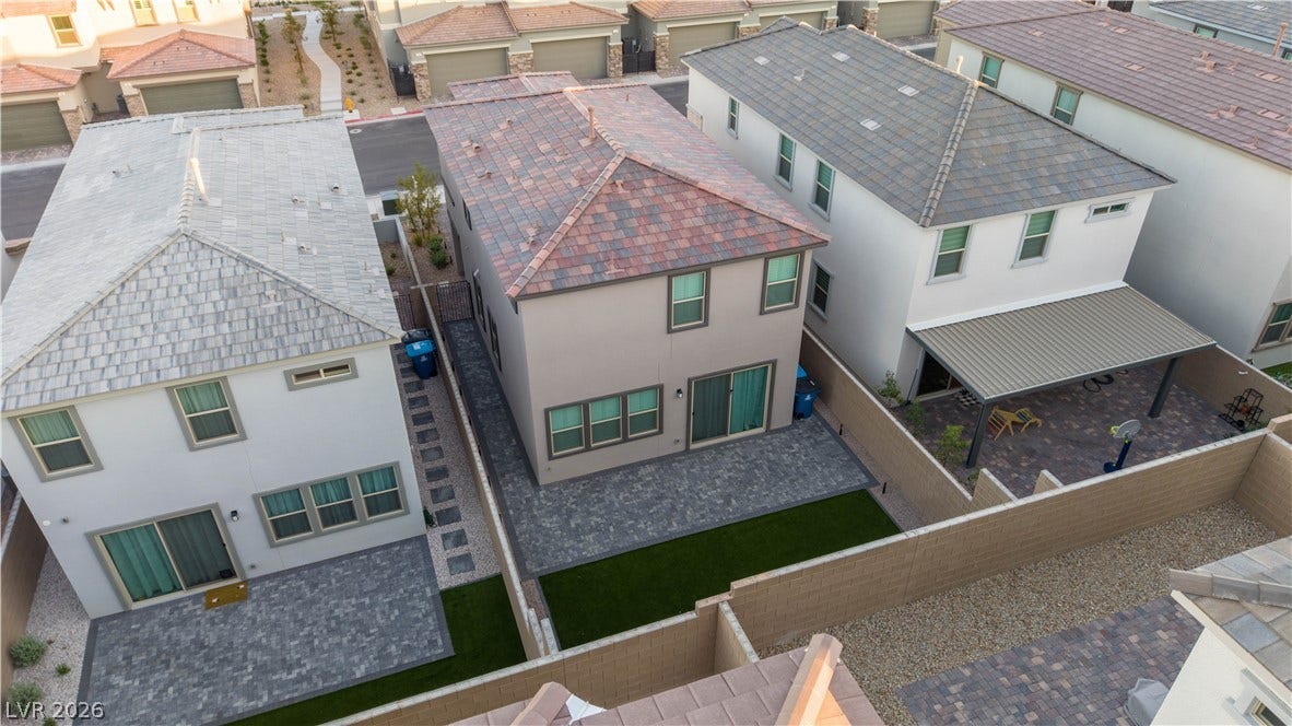 A high-angle view reveals the modern stucco exterior, tiled roofline, and paved patio space.