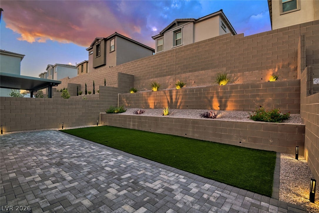 A beautifully terraced backyard features meticulous stone retaining walls and integrated landscape lighting.
