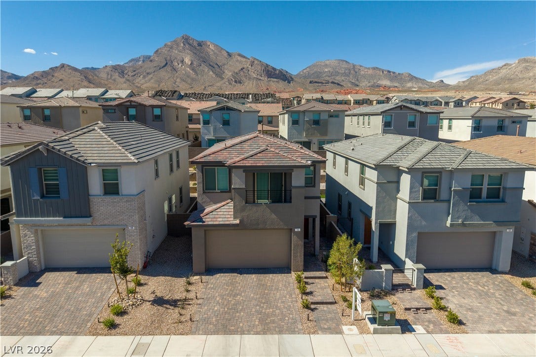 Majestic mountain peaks rise sharply behind a contemporary neighborhood of two-story homes.