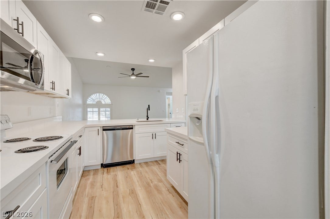 3676 Renovah Street, #205, Las Vegas, NV 89129 White cabinetry paired with clean countertops borders this light wood-floored cooking space.