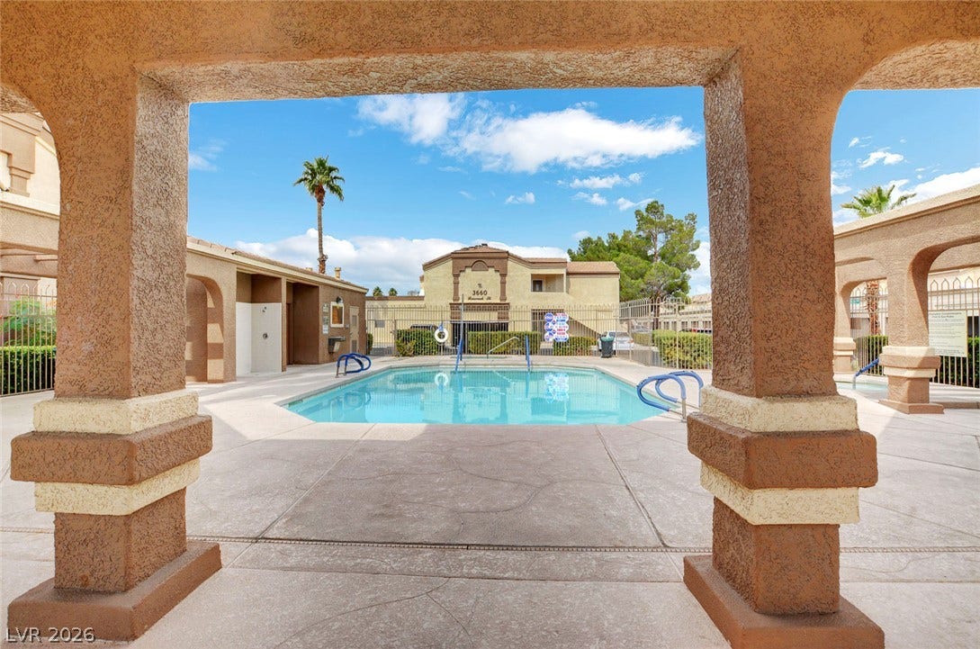3676 Renovah Street, #205, Las Vegas, NV 89129 Stucco pillars frame a view of the community swimming pool under blue skies.
