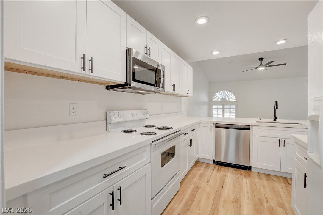 3676 Renovah Street, #205, Las Vegas, NV 89129 Crisp white cabinetry, solid stone countertops, and durable wood-look flooring define this streamlined kitchen.