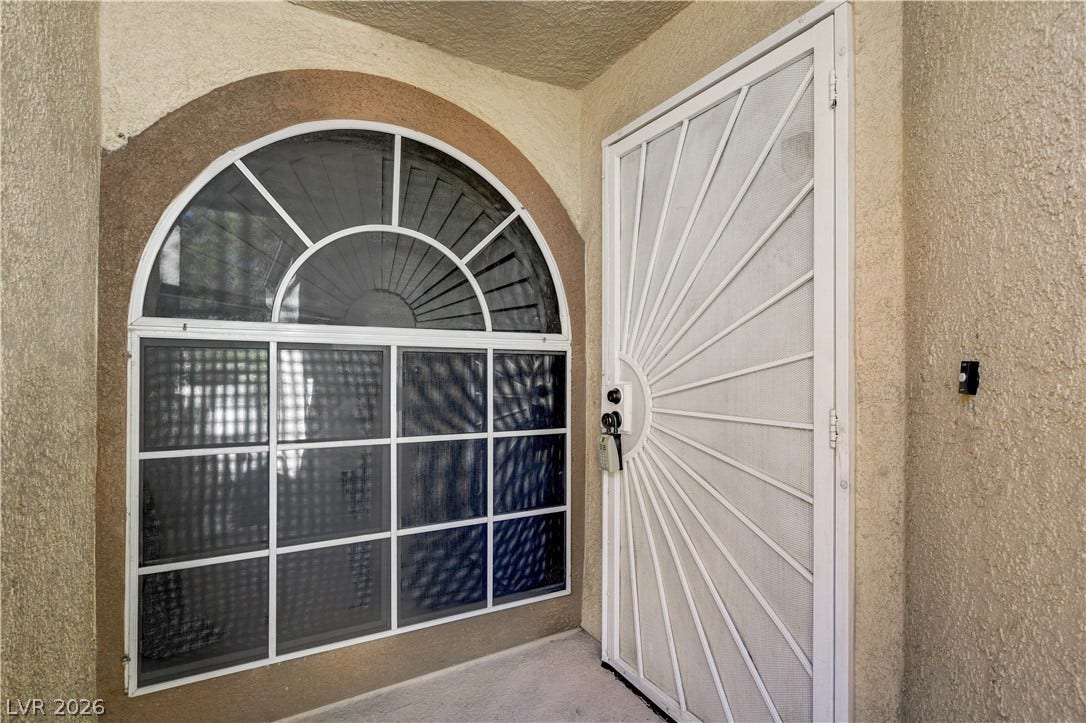 3676 Renovah Street, #205, Las Vegas, NV 89129 A stucco entryway features a classic arched window alongside a security screen door.