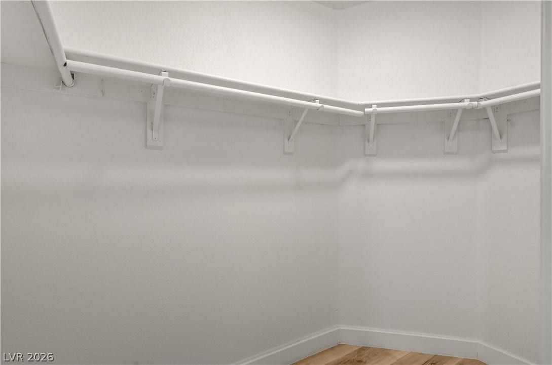 3676 Renovah Street, #205, Las Vegas, NV 89129 A spacious walk-in closet includes wrap-around hanging rods and wood-grain flooring.