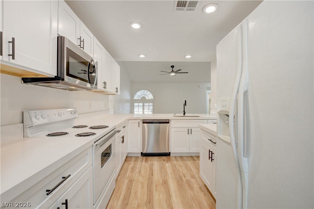 3676 Renovah Street, #205, Las Vegas, NV 89129 Crisp white cabinetry paired with modern solid-surface countertops defines this well-organized cooking space.