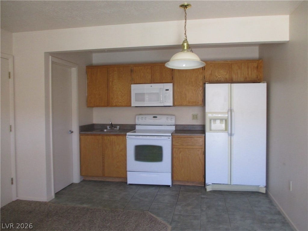 100 Pulsipher Lane, #1205, Mesquite, NV 89027 Oak cabinetry and tile flooring define this functional kitchen space.