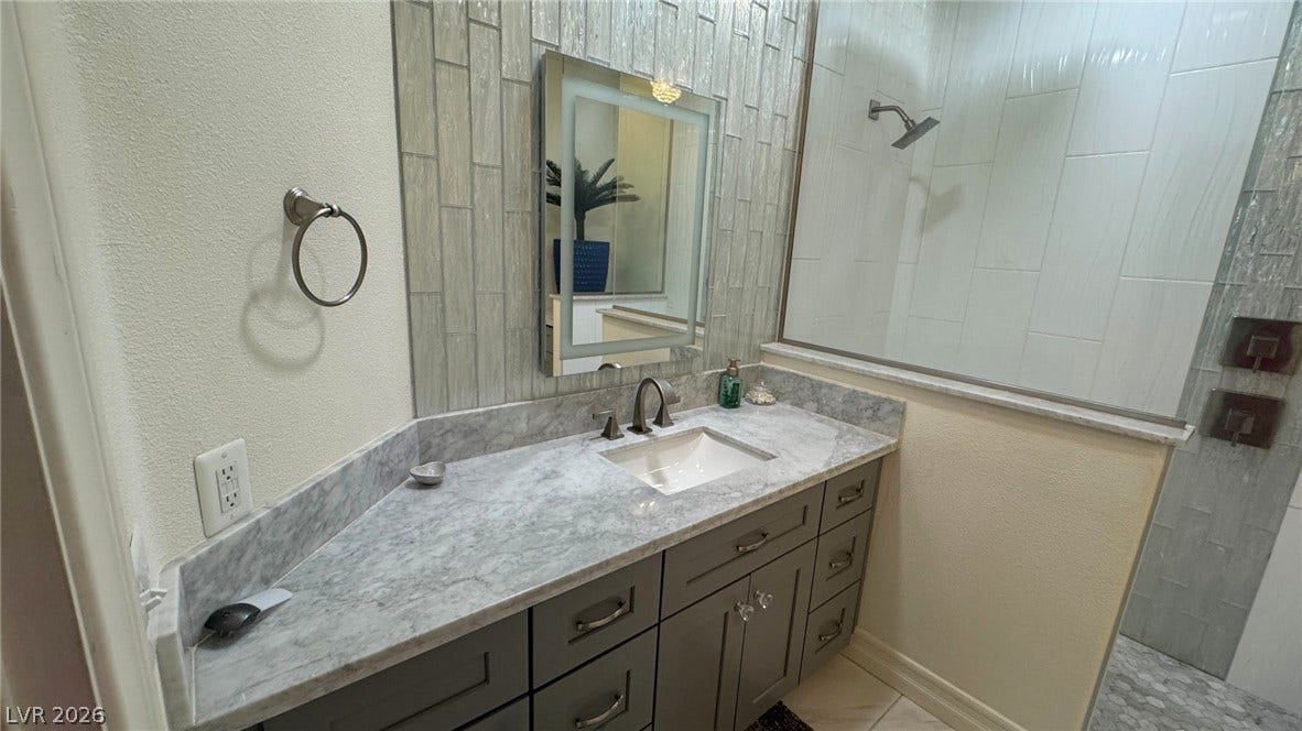 8304 Apple Glaze Avenue, #203, Las Vegas, NV 89145 Polished stone countertops pair with vertical wall tile in this sleek modern bathroom.